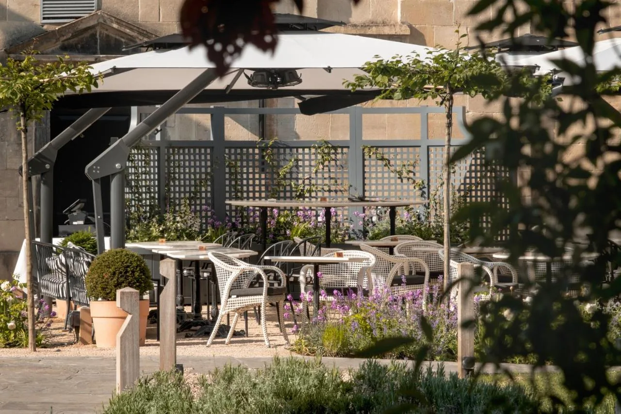 Tables and chairs under an umbrella in the hotel garden